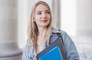 1-portrait-of-a-young-freelancer-girl-holding-a-notebook-folder-and-standing-behind-the-ancient-building_101969-1252_i