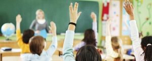 Children are raised hands in classroom.